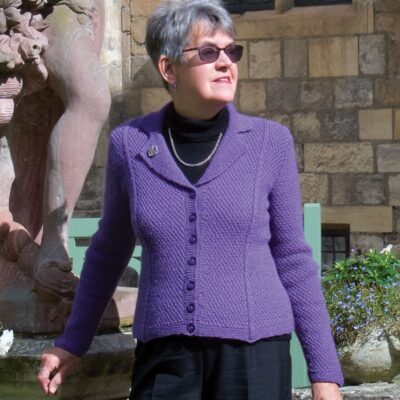 Woman wearing woolen jacket knitting kit made from border leicester yarn. Lunch i York pattern, knitted in DK yarn, textured jacket.